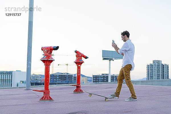 Young man with a skateboard using cell phone