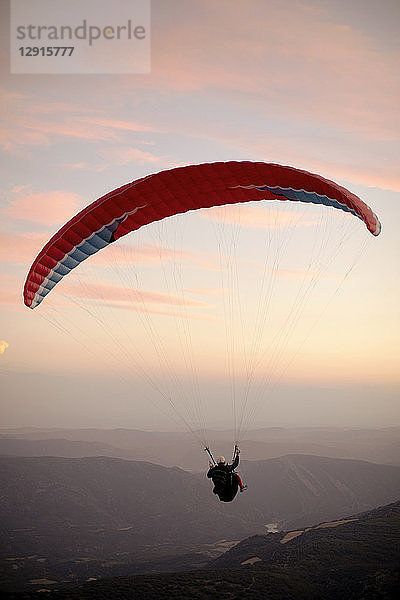 Paraglider flying with mountains in the background during sunset
