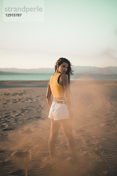 Portrait of teenage girl standing on the beach at sunset