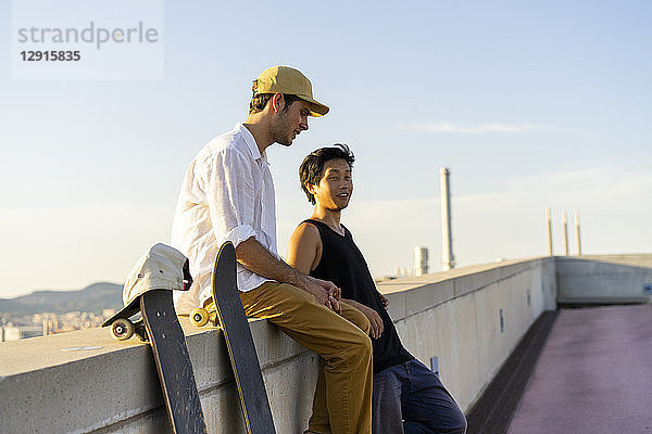 Two young men resting next to skateboards at a wall