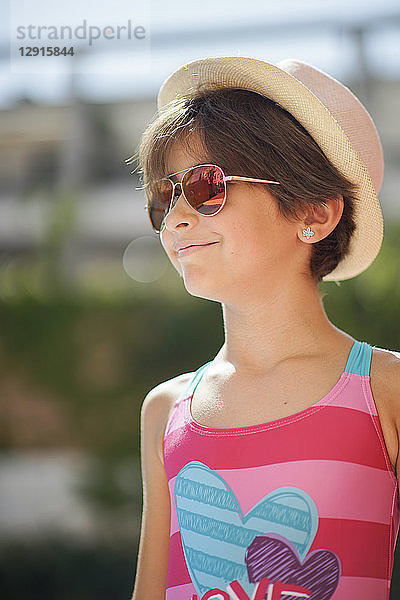 Portrait of young girl with sunglasses and sun hat  looking sideways