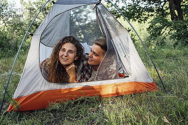 Young couple camping in nature  lying in tent  taking a break