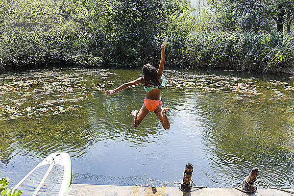 Carefree girl jumping into pond