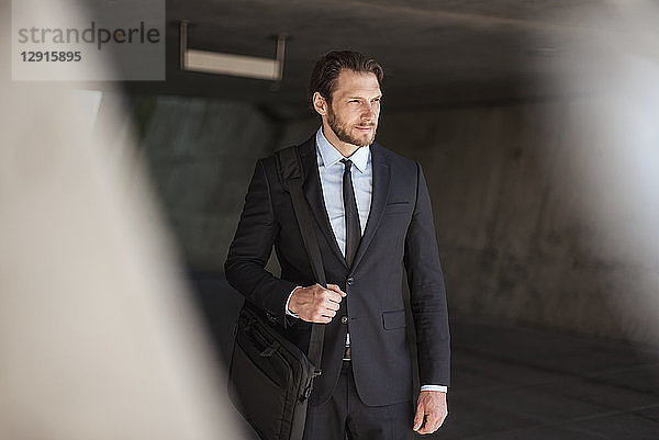 Confident businessman with laptop bag standing in underpass