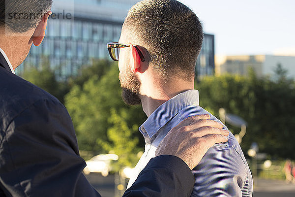 Older businessman placing hand on shoulder of younger businessman