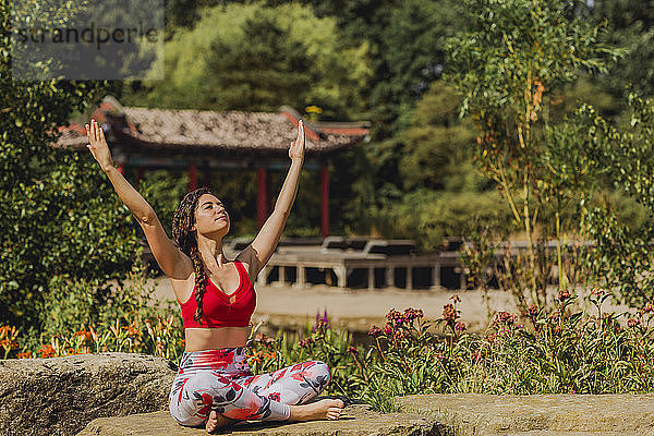 Young woman practicing Pilates in an urban park  raised arms