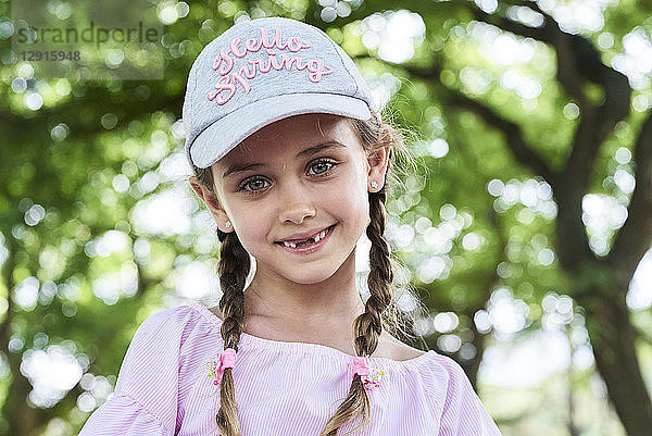 Portrait of little girl with green eyes braids and cap  smiling