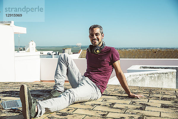 Smiling man sitting on roof  enjoying summer