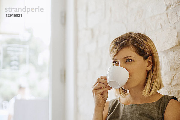 Young woman drinking cup of coffee