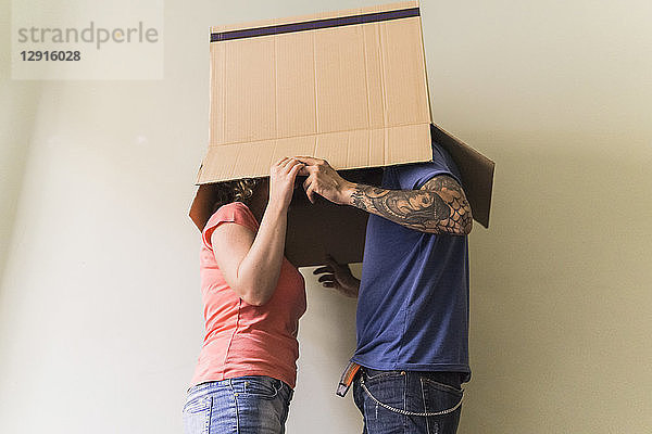 Couple with heads together in cardboard box at new home