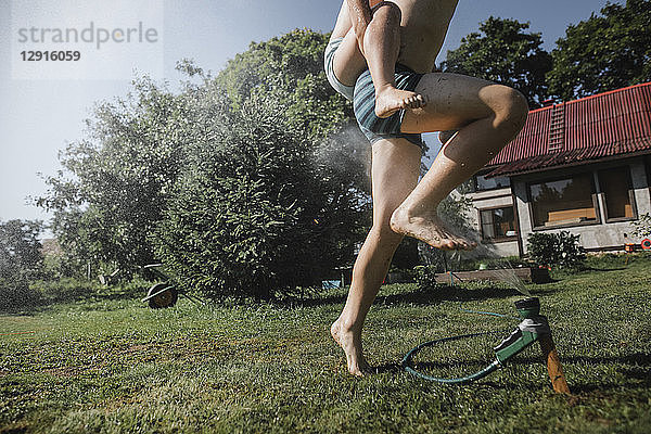 Brother and sister playing with garden hose in garden