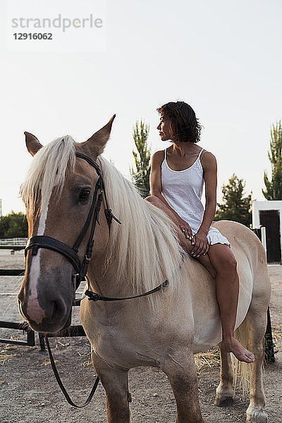 Barefoot woman sitting bareback on horse