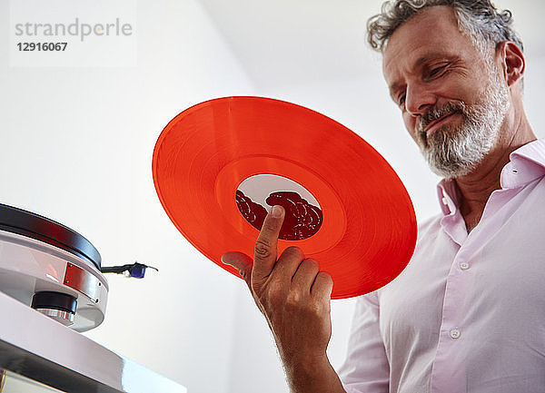 Smiling mature man holding red vinyl record