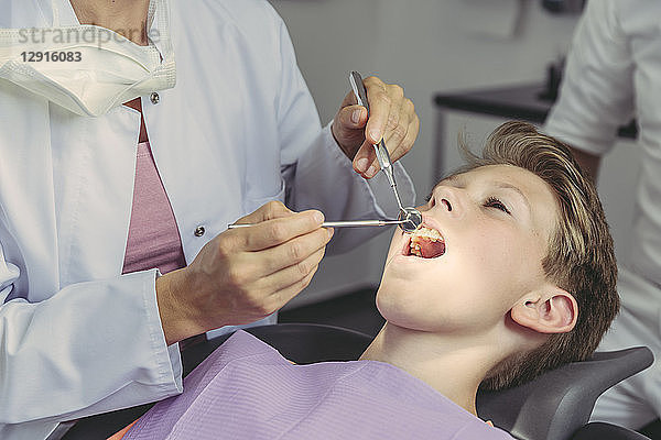 Dentist examining boy's teeth with dental instruments