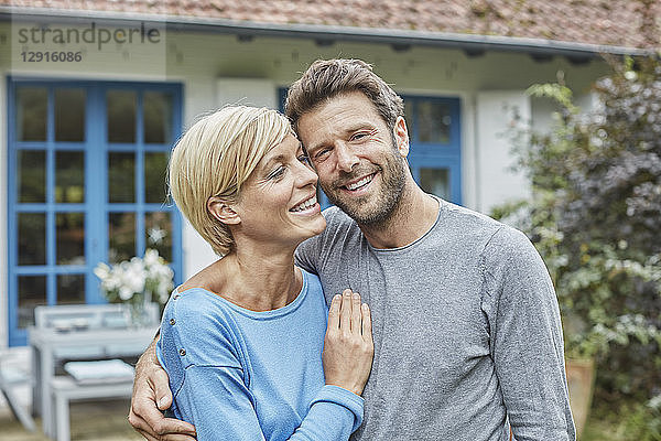 Portrait of smiling couple standing in front of their home