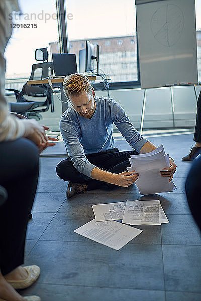 Businessman organising papers on the floor in office