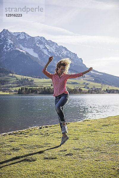 Austria  Tyrol  Walchsee  happy woman jumping at the lake