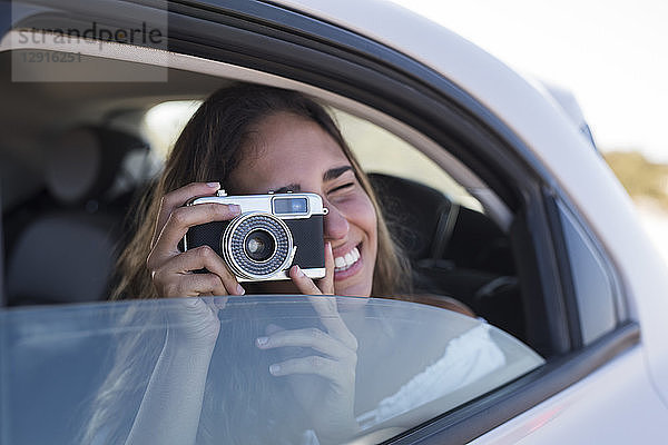 Woman sitting in car  taking pictures with a camera