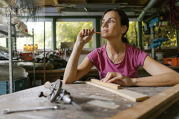 Mature woman at workbench in her workshop thinking