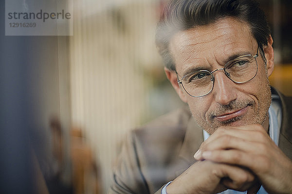 Mature businessman sitting in coffee shop  looking out of window