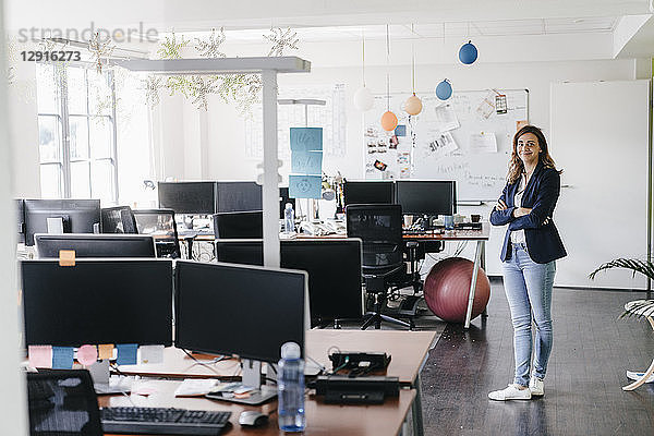 Confident businesswoman standing smiling in office
