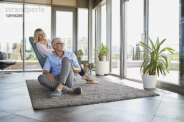 Mature couple relaxing at home looking out of window