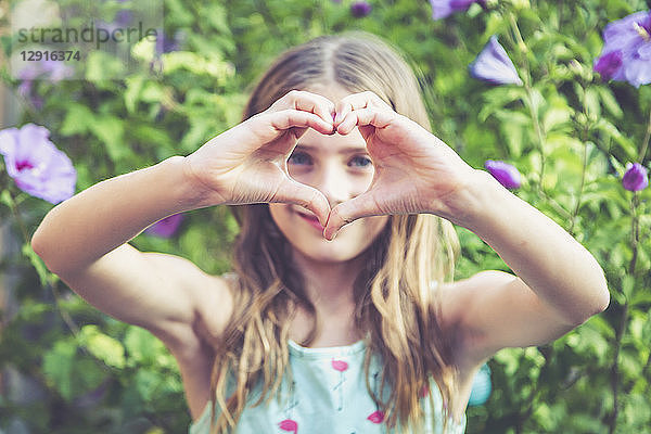 Young girl making a heart shape with her fingers