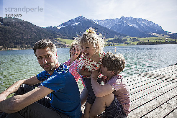 Austria  Tyrol  Walchsee  happy family sitting on a jetty at the lakeside