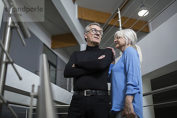 Senior woman supporting senior businessman on office stairs