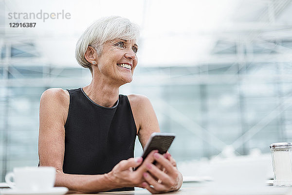 Smiling senior woman with cell phone in a cafe