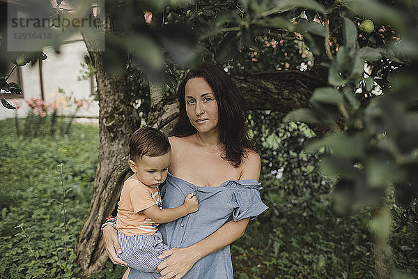 Portrait of mother holding baby in garden