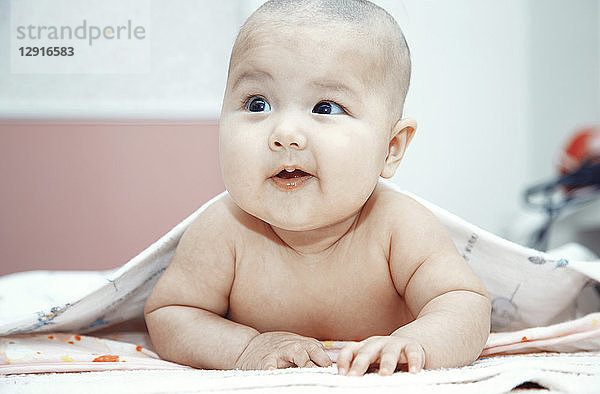 Smiling baby lying naked on bed  portrait