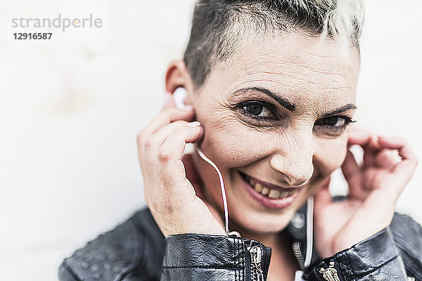 Portrait of smiling punk woman listening to music with earbuds