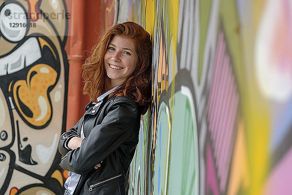 Italy  Finale Ligure  portrait of smiling teenage girl leaning against mural