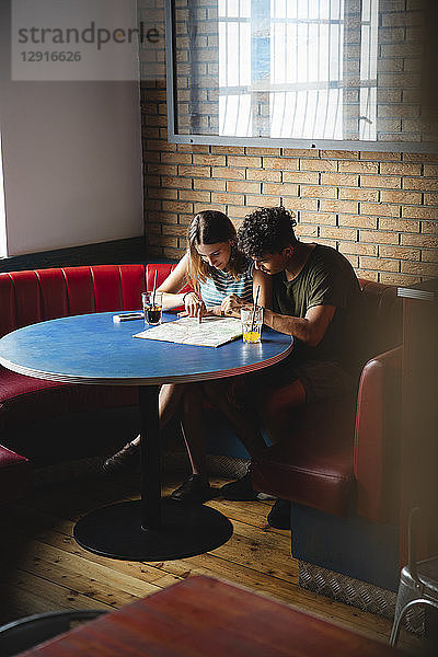 Young couple sitting at table in a cafe with map