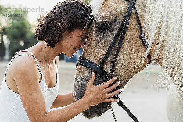 Woman head to head with riding horse