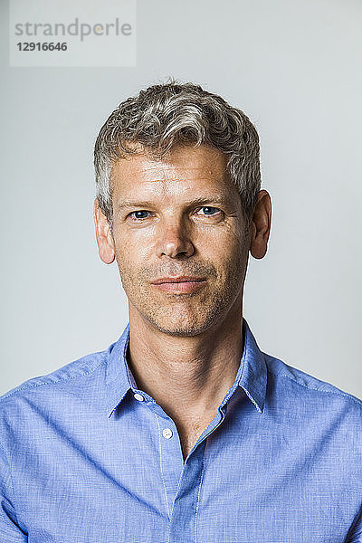 Portrait of mature man with grey hair wearing blue shirt