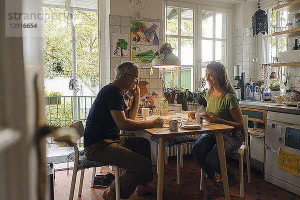 Mature couple sitting at kitchen table at home