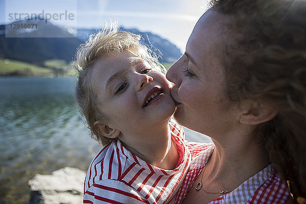 Austria  Tyrol  Walchsee  mother kissing happy daughter at the lake