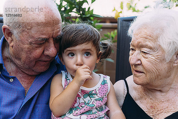Grandparents looking at baby girl sucking thumb
