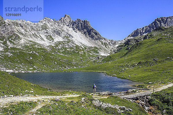 Austria  Vorarlberg  Hiker standing at mountain lake