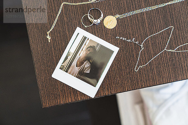 Instant photo of young woman next to jewelry on wooden table