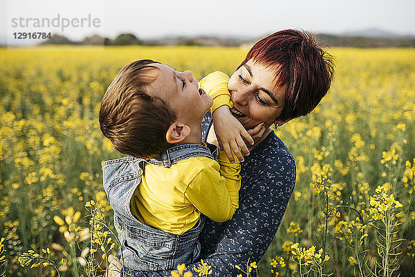 Mother having fun with her little son in a rape field