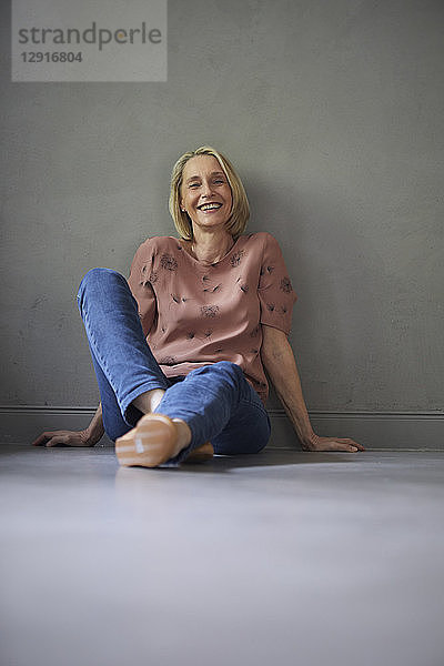 Portait of smiling mature woman at home sitting on the floor