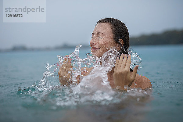 Young woman bathing in lake splashing with water