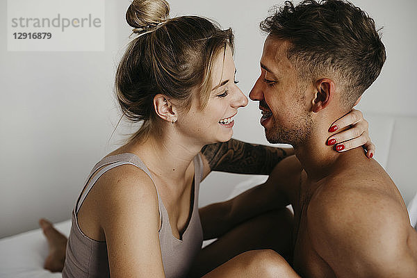 Happy young couple in bed smiling at each other