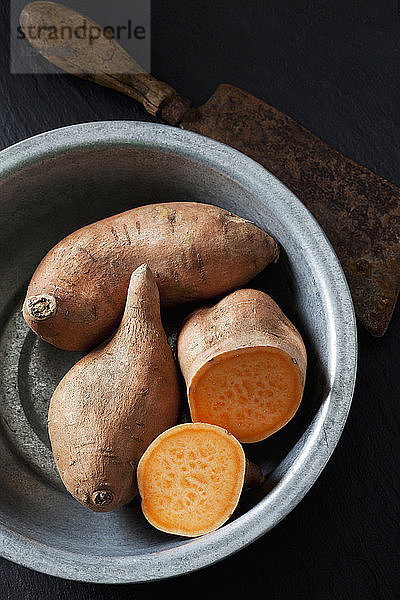 Sliced and whole sweet potato in metal bowl
