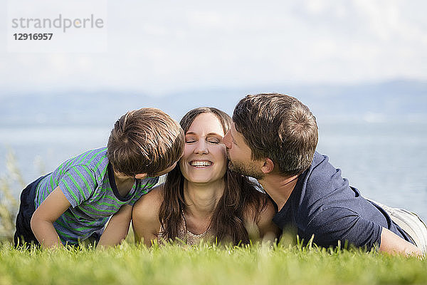 Germany  Friedrichshafen  Lake Constance  father and son kissing happy mother