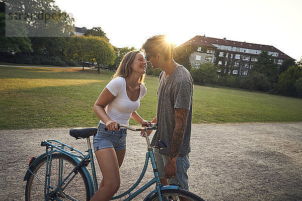 Young woman with bicycle  kissing her boyfriend in park