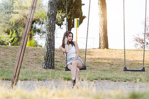 Young woman sitting on a swing on a playground